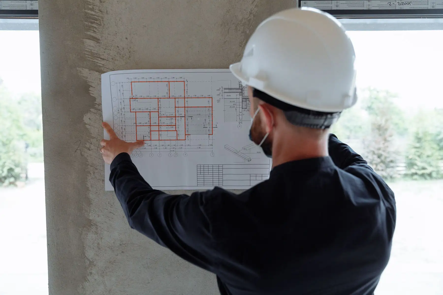 An engineer in a hard hat checking drawings on site